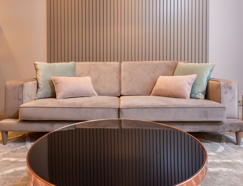 A pristine, white upholstered sofa with tufted back and rolled arms, positioned against a white paneled wall in a well-lit room. The sofa's fabric appears clean and fresh, with no visible stains or dust, reflecting recent deep cleaning. The room features a wooden floor, and the lighting highlights the sofa's smooth surface and the room's minimalist, elegant decor. The scene emphasizes surface cleaning and maintenance, consistent with domestic cleaning services provided by Knightsbridge Carpet Cleaning, ensuring hygiene and surface sanitation in residential settings.
